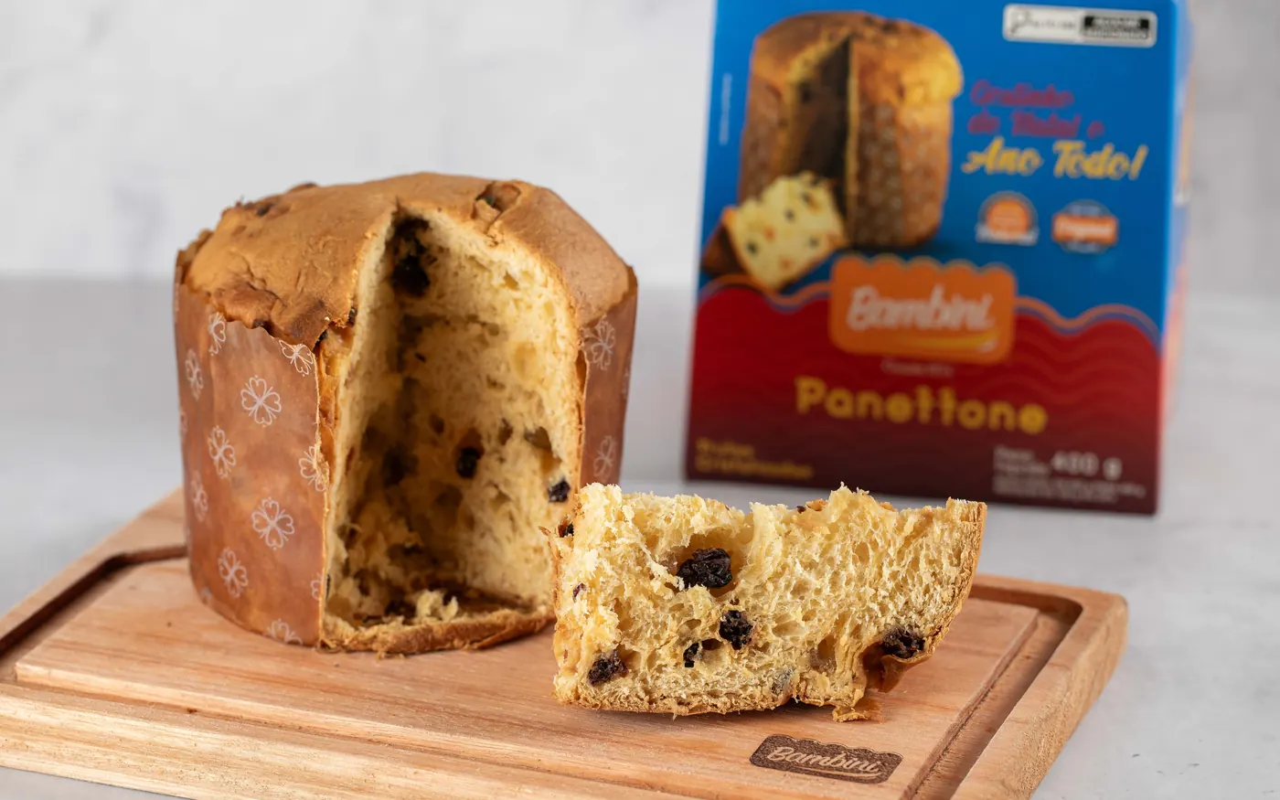 Panettone Bambini de Frutas Cristalizadas aberto sobre tábua, ao lado da caixa